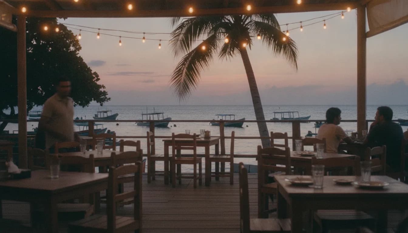 Terraza frente al mar al atardecer, con luces colgantes y lanchas al fondo